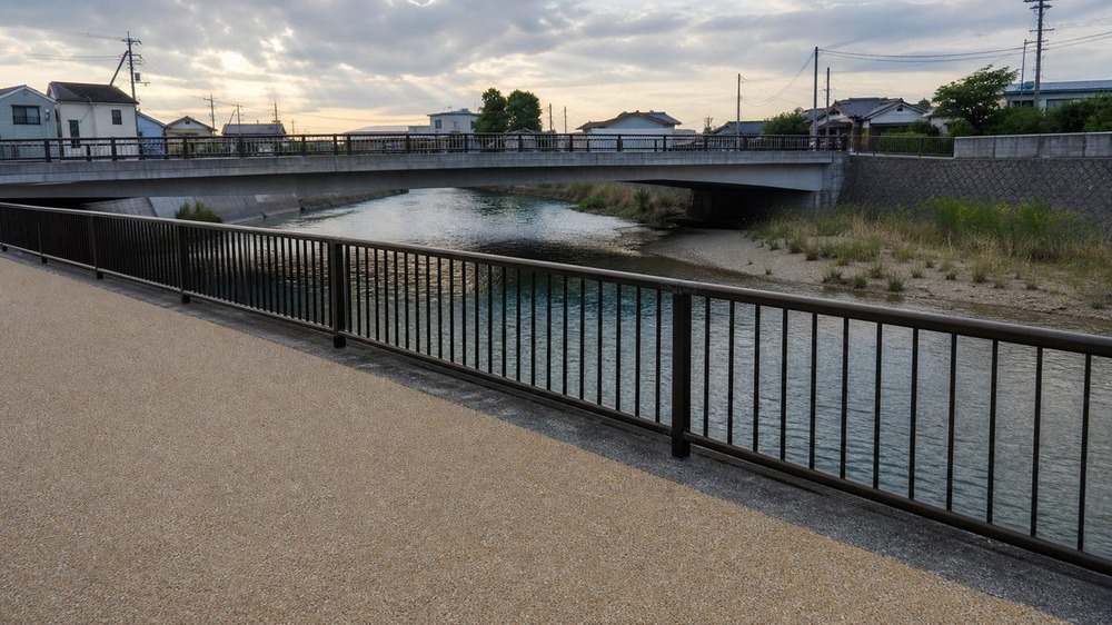 橋の影と泥砂の岸際がある少し広い都市河川