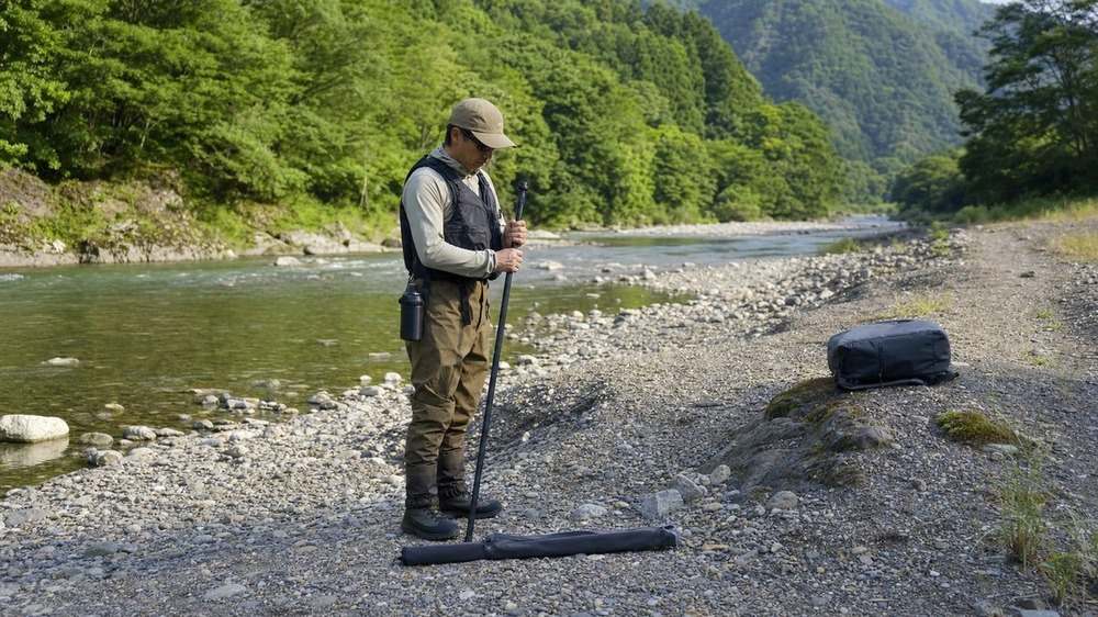 救命胴衣とウェーディングシューズを着け清流釣りの装備を確認するアングラー